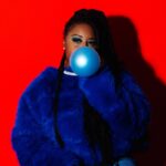 Woman blowing a blue bubble with gum