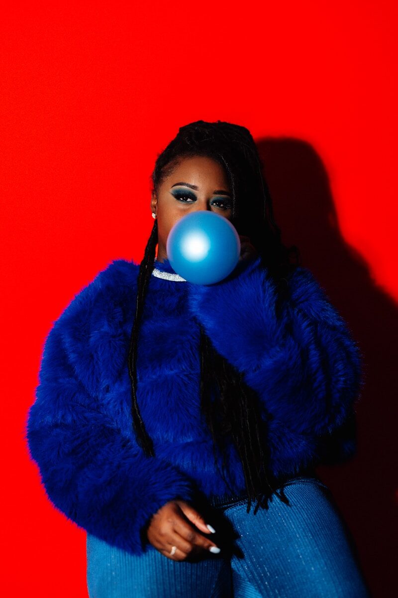 Woman blowing a blue bubble with gum